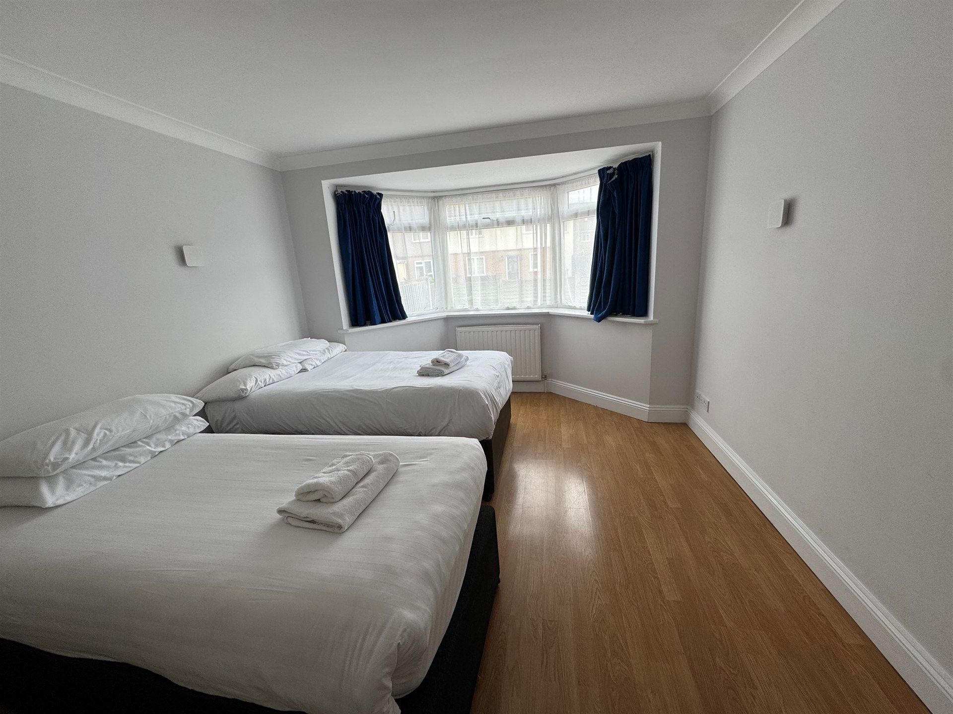 A bedroom with two beds and a large window.
