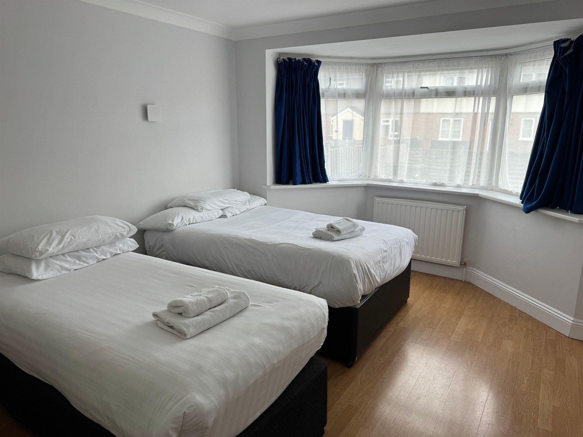 A bedroom with two beds and a large window.