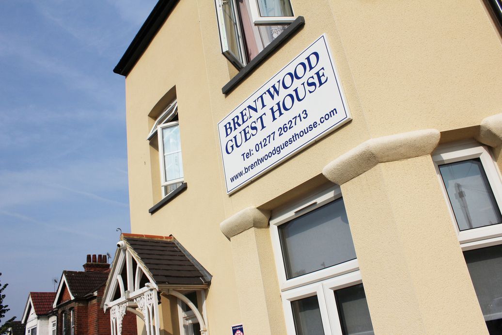 A yellow building with a sign that says brentwood guest house