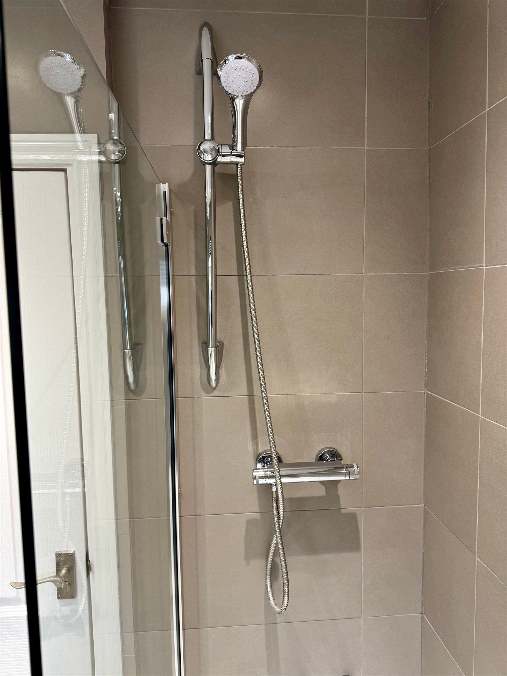 A shower stall with a shower head and a glass door.