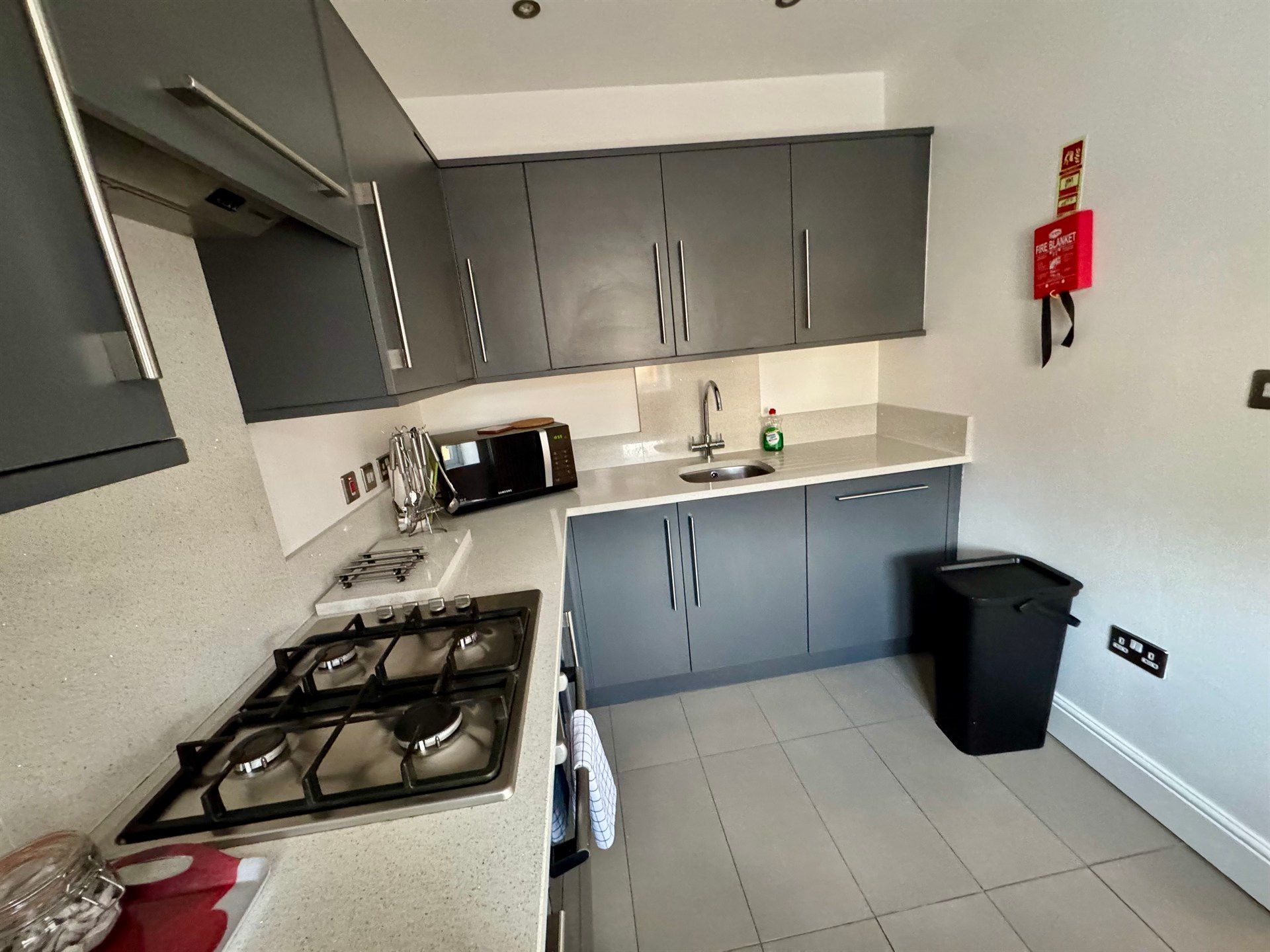 A kitchen with a stove and a trash can