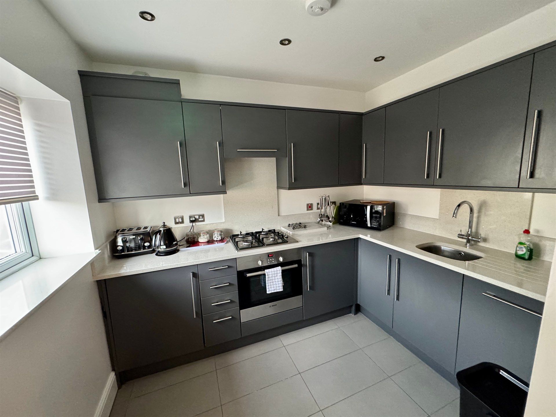 A kitchen with gray cabinets and white counter tops