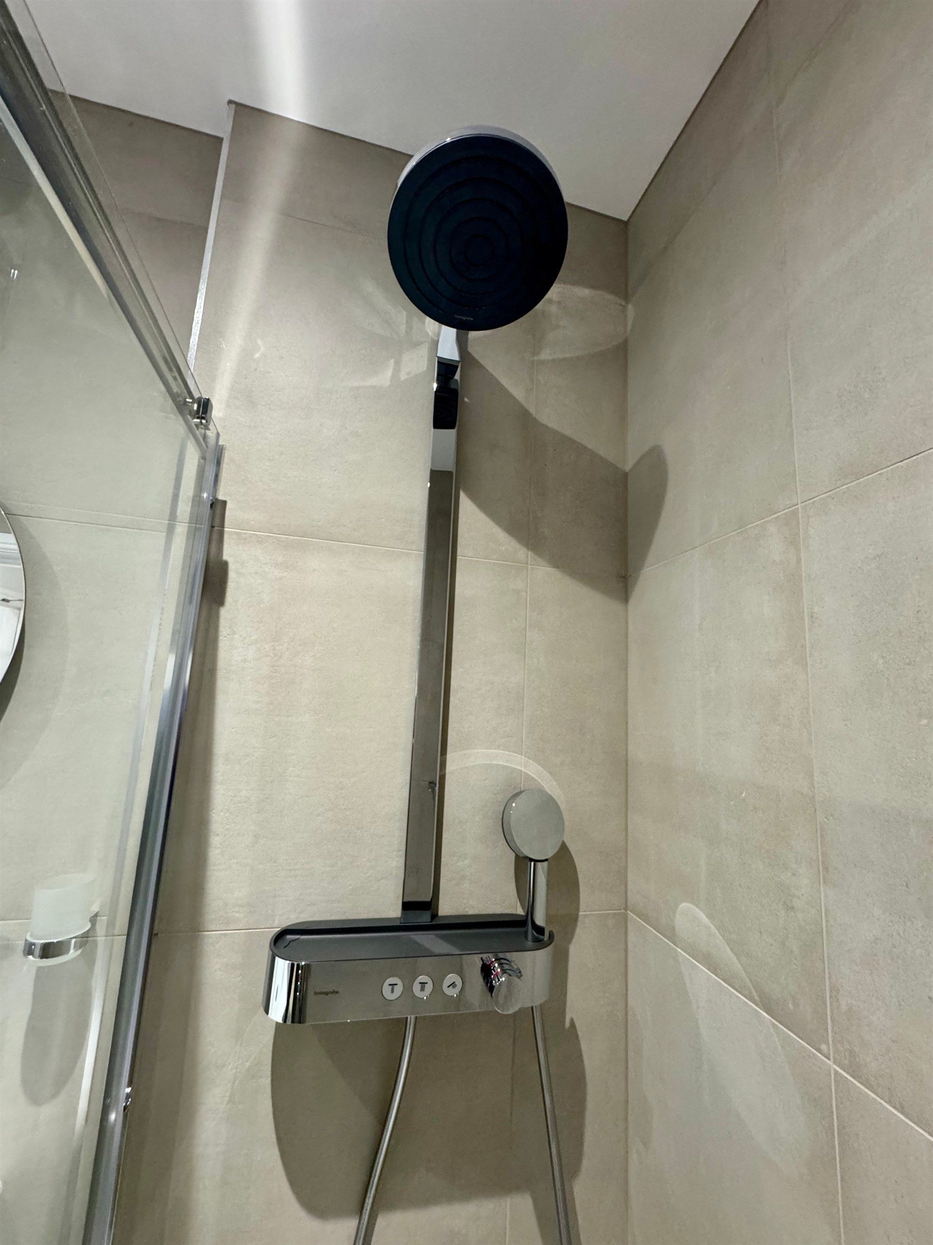 A shower head is hanging from the ceiling in a bathroom.
