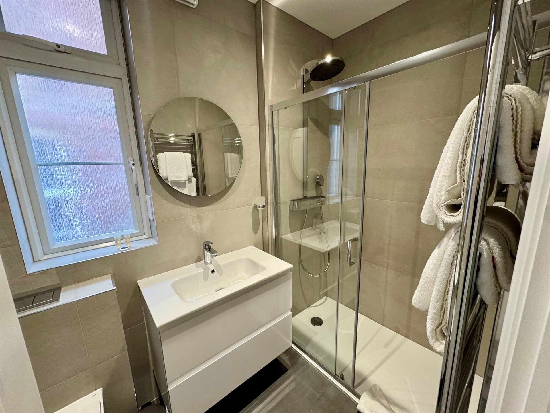 A bathroom with a sink , mirror , and shower stall.