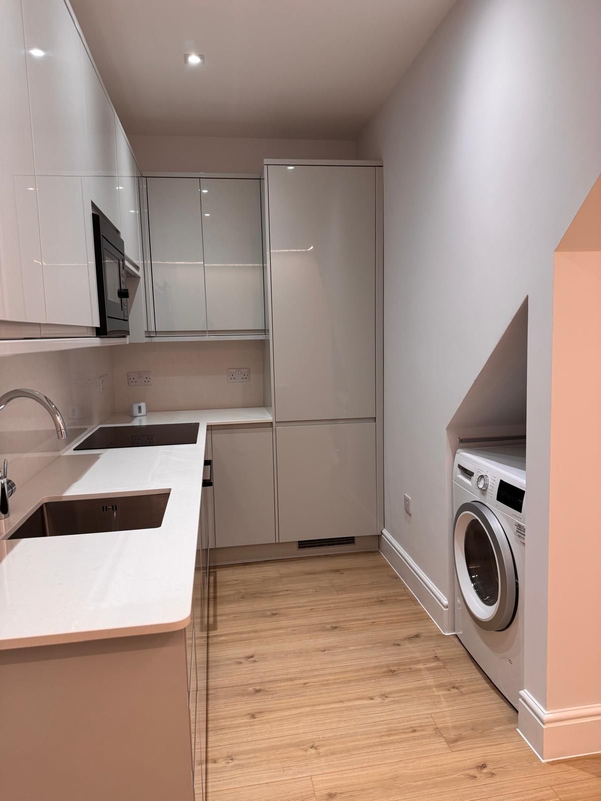 A kitchen with a sink , refrigerator , washer and dryer.