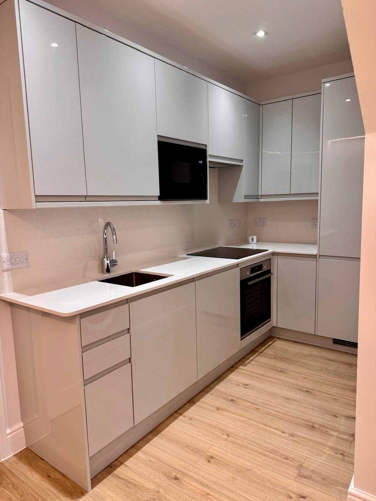 A kitchen with white cabinets and wooden floors