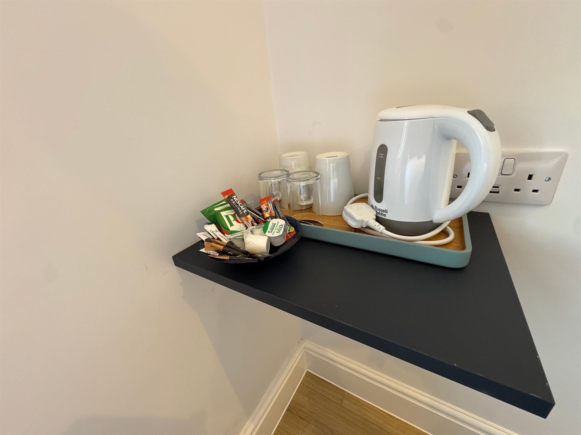 A kettle is sitting on a shelf next to a bowl of coffee.