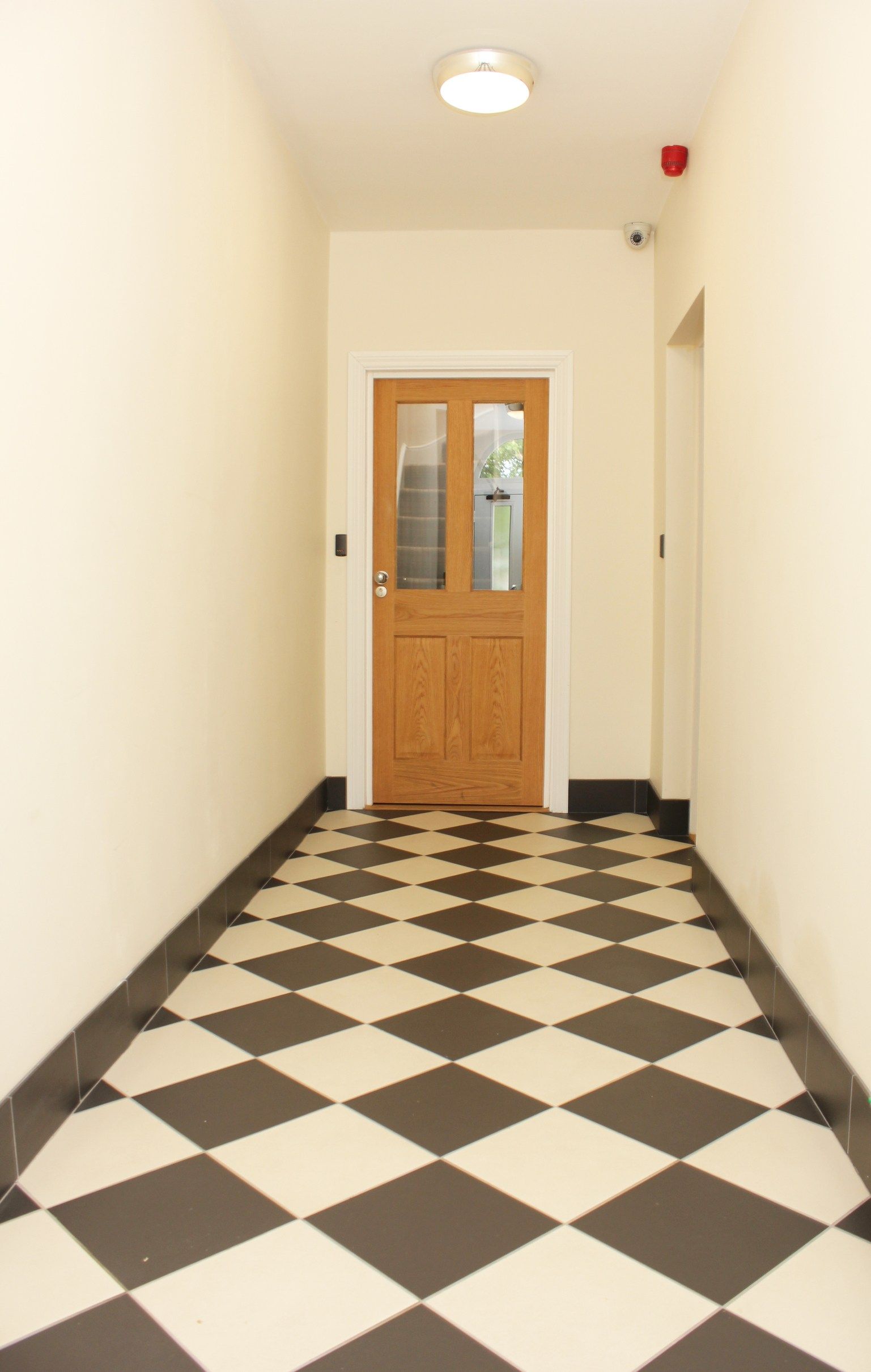 A hallway with a checkered floor and a door