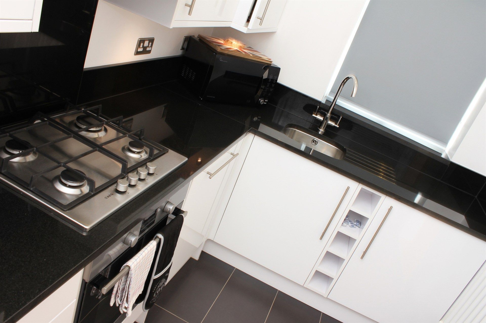 A kitchen with black counter tops and white cabinets