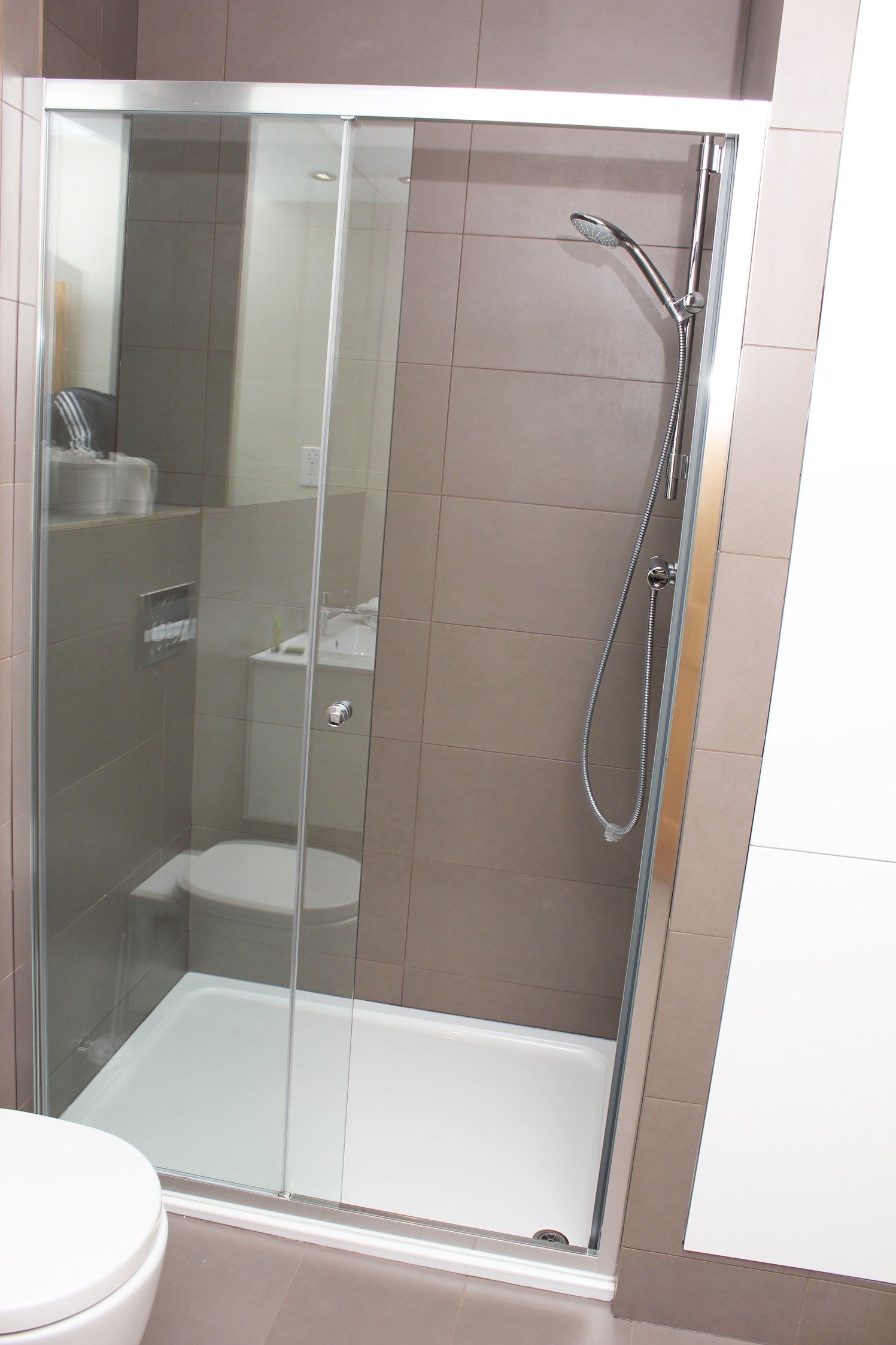 A bathroom with a sliding glass shower door and a toilet