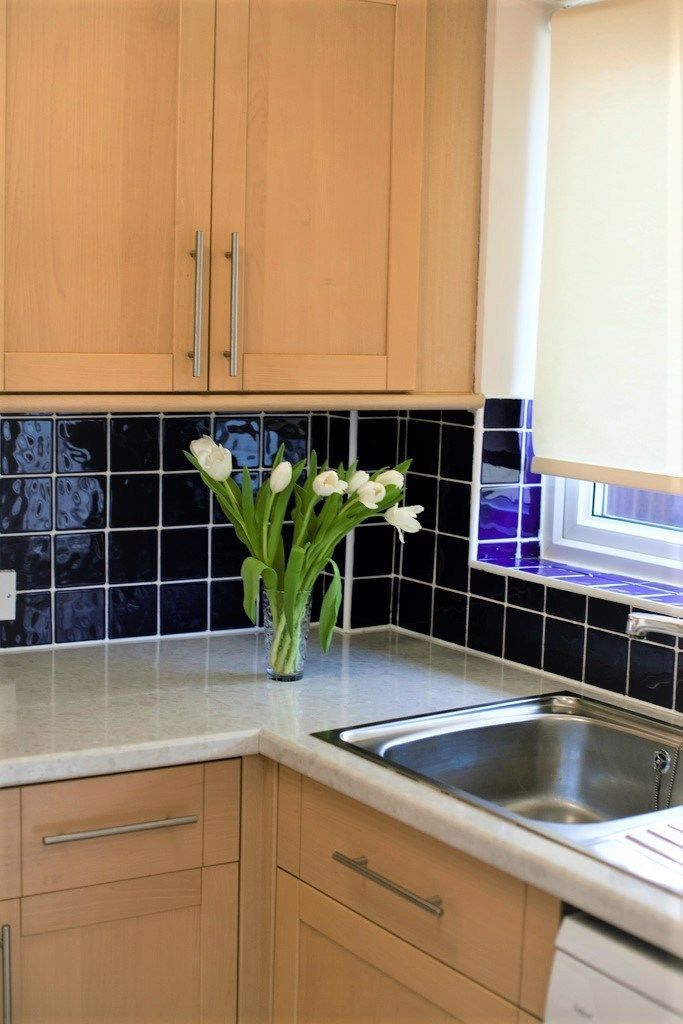 A kitchen counter with a vase of flowers on it