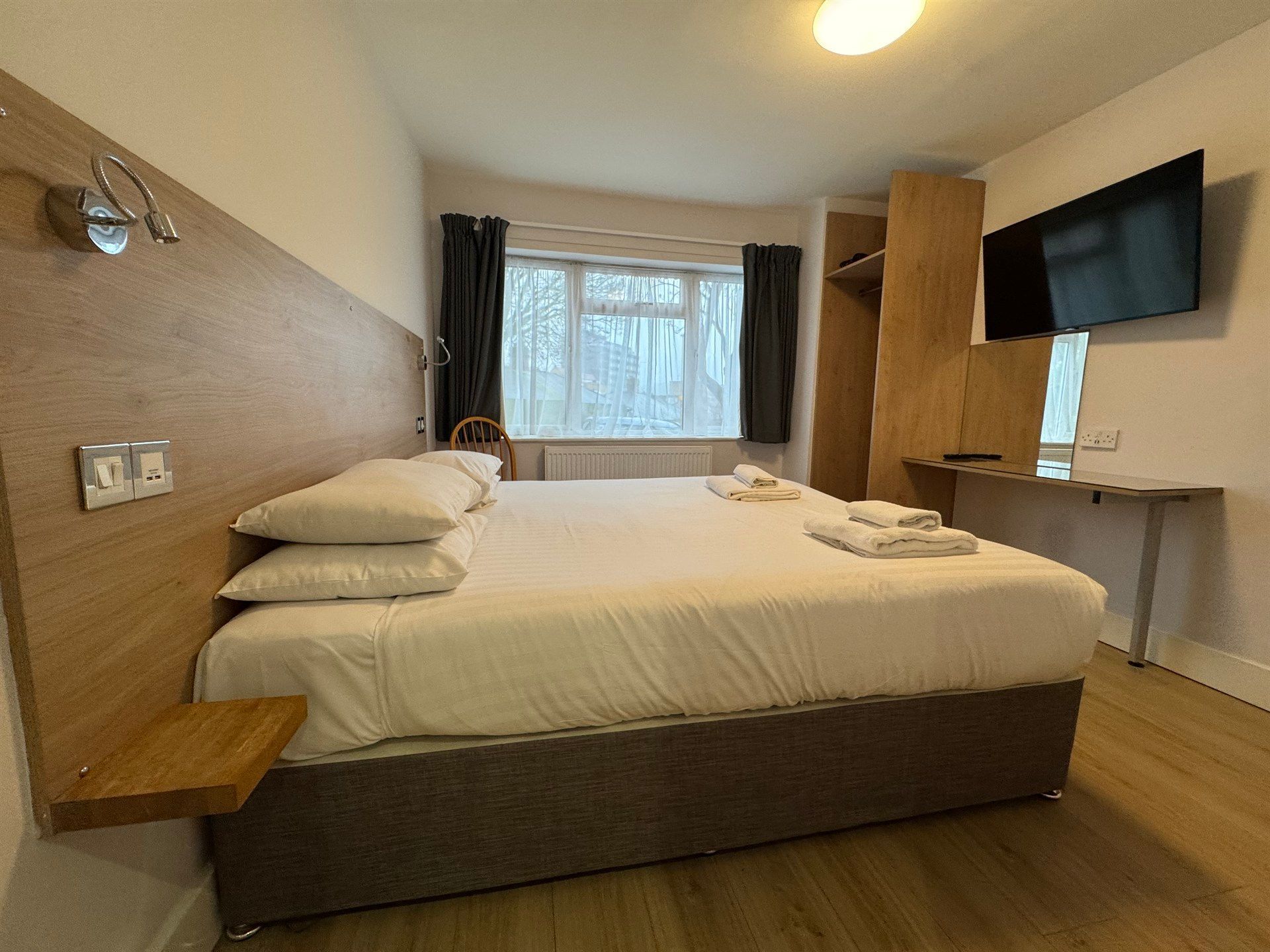 A hotel room with a king size bed and a flat screen tv.