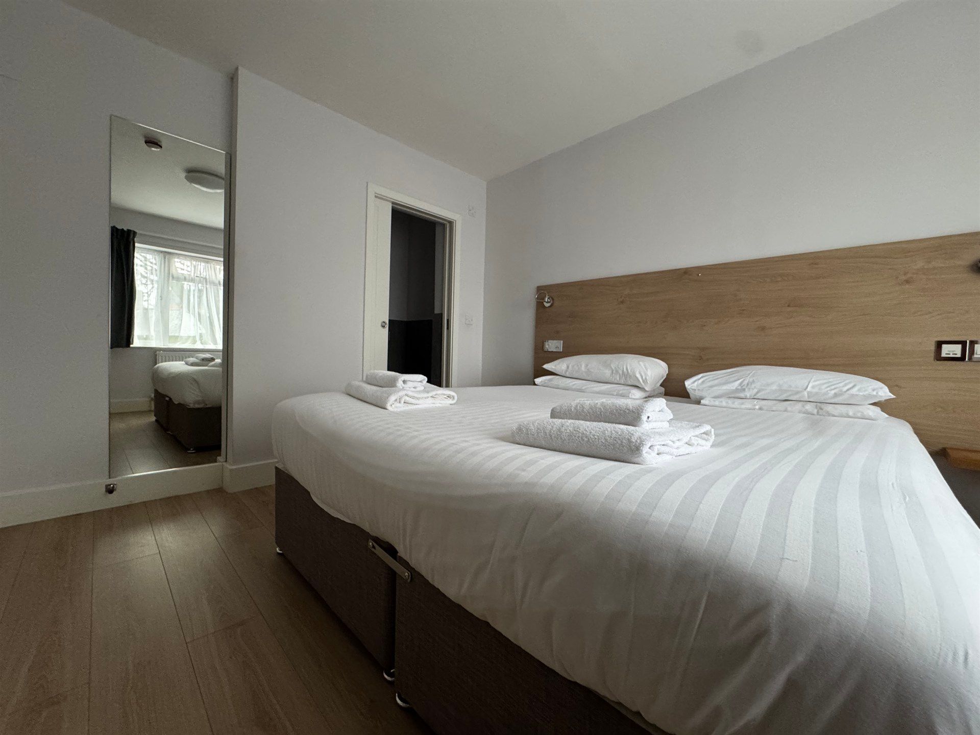 A hotel room with two beds and a mirror.