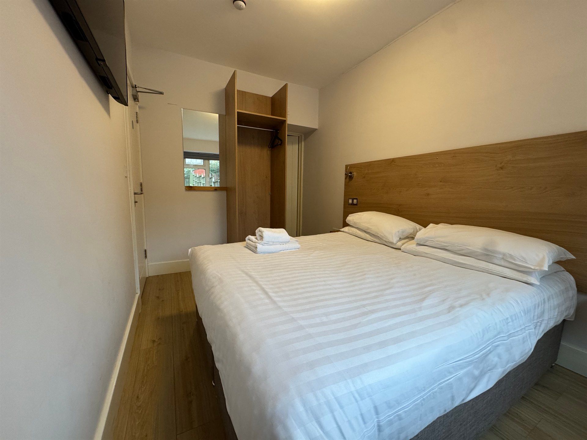 A hotel room with a large bed and a wooden headboard.