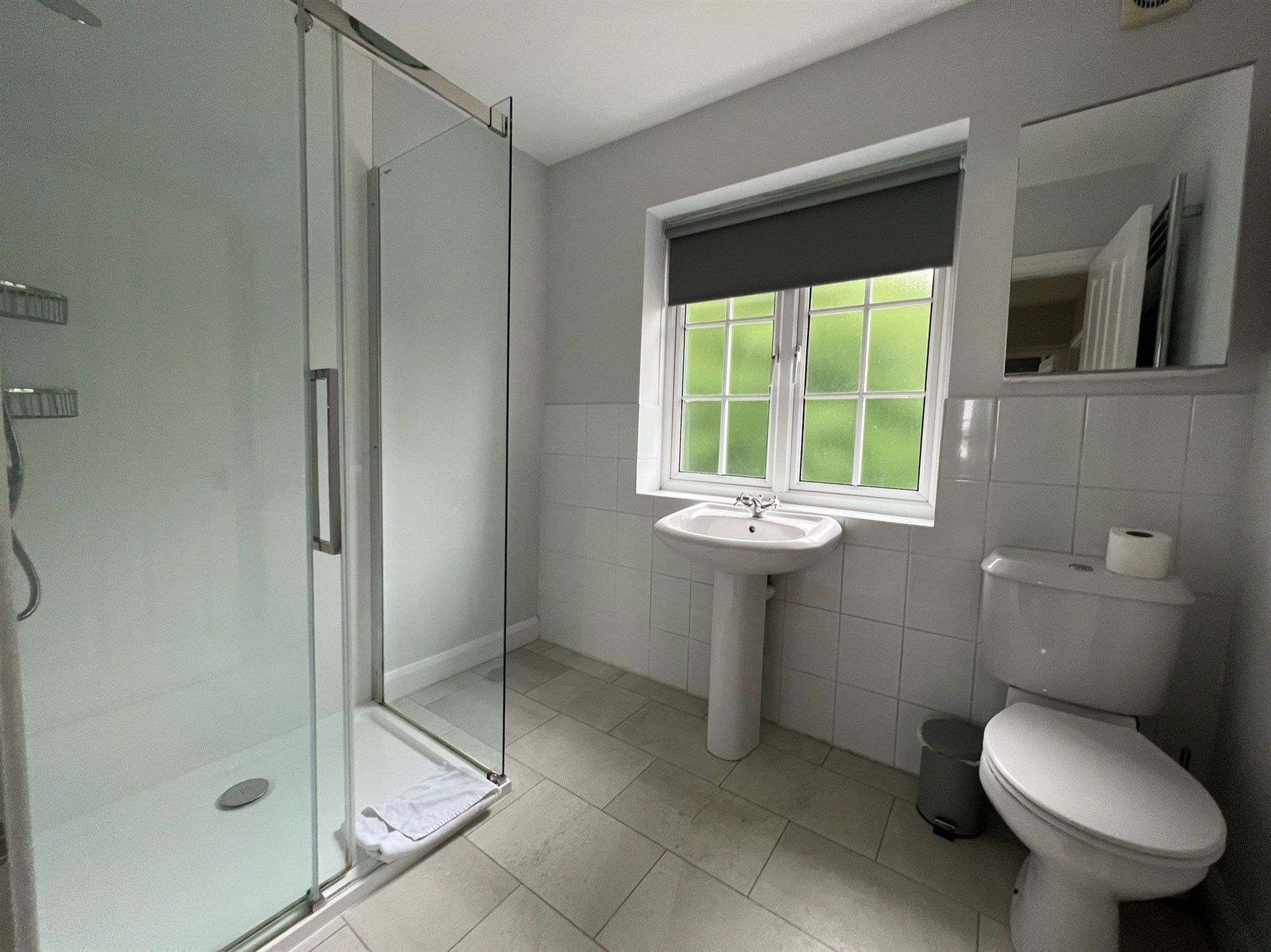 A bathroom with a toilet , sink and shower.