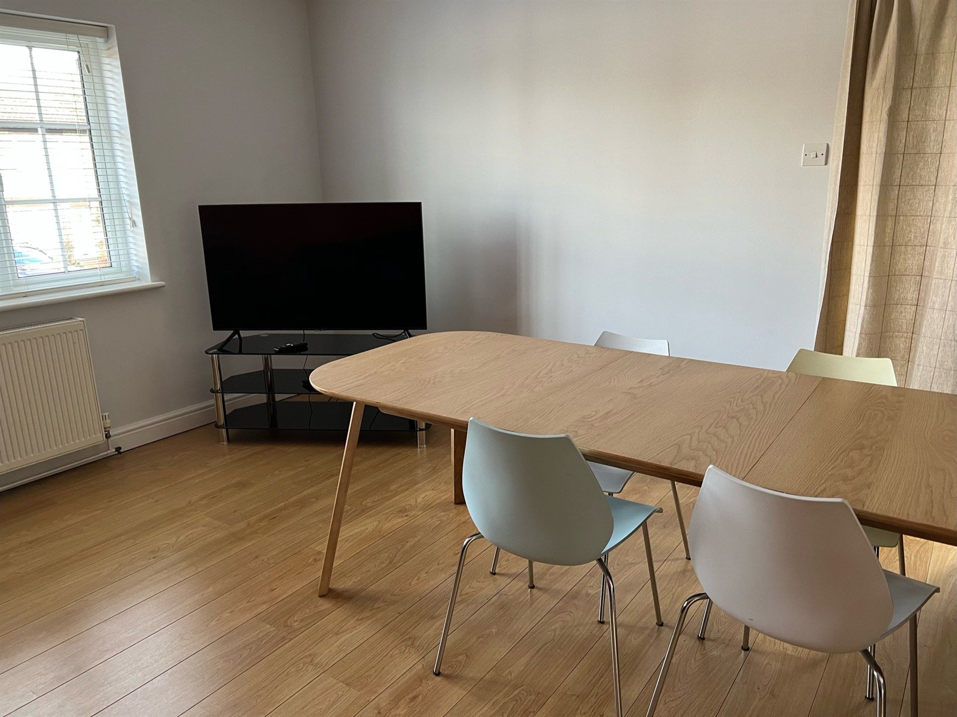 A living room with a table and chairs and a flat screen tv.