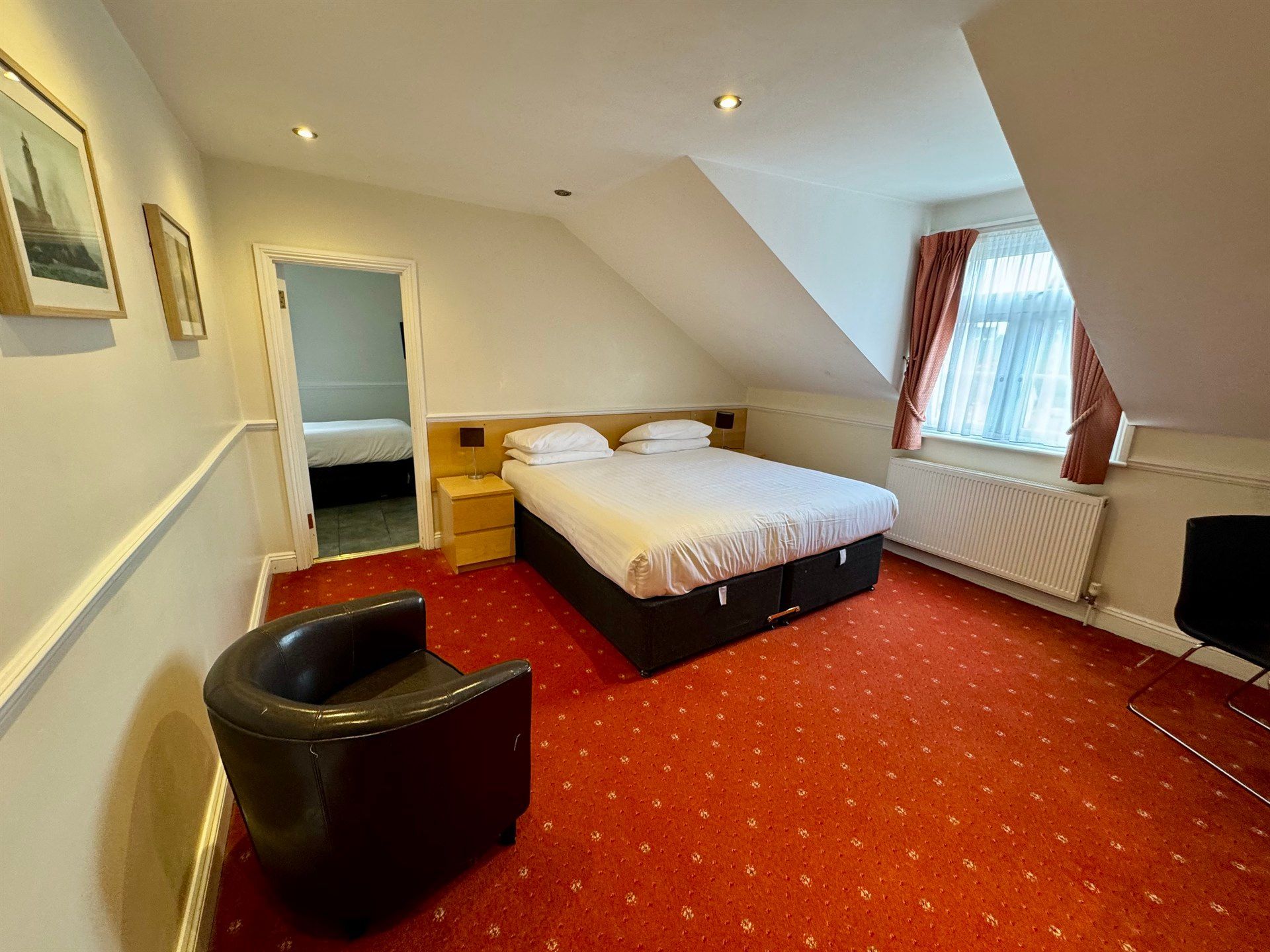 A hotel room with a bed , chair , and window.