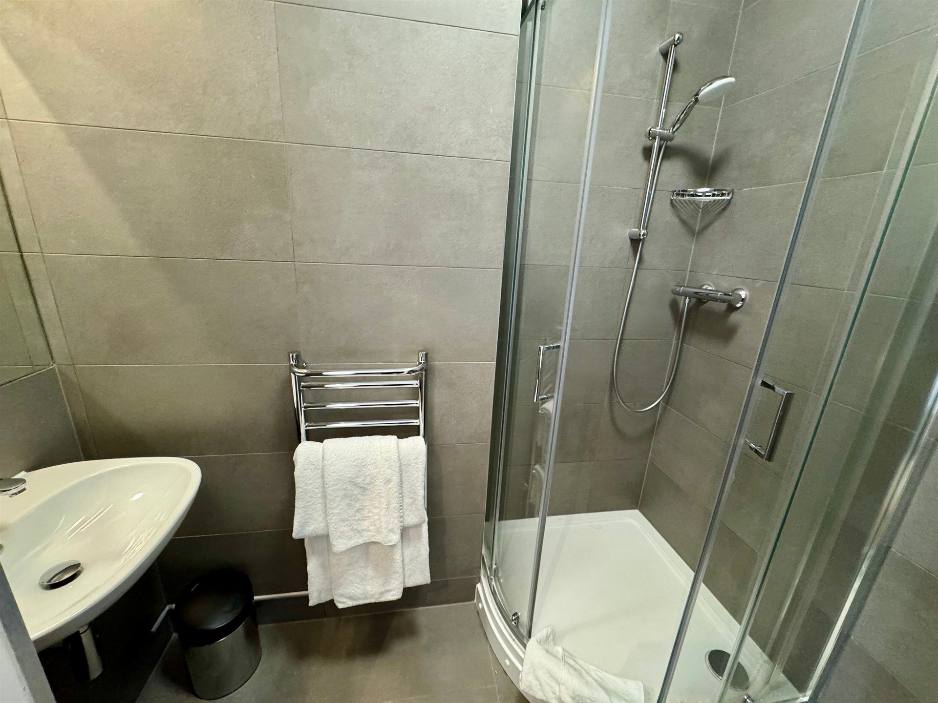 A bathroom with a sink , shower , and towel rack.