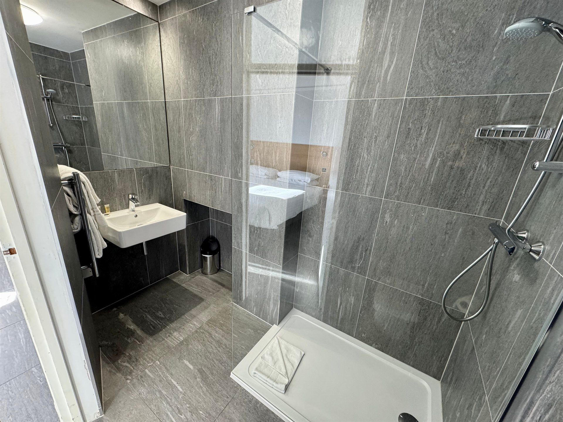 A bathroom with a sink , shower , and mirror.