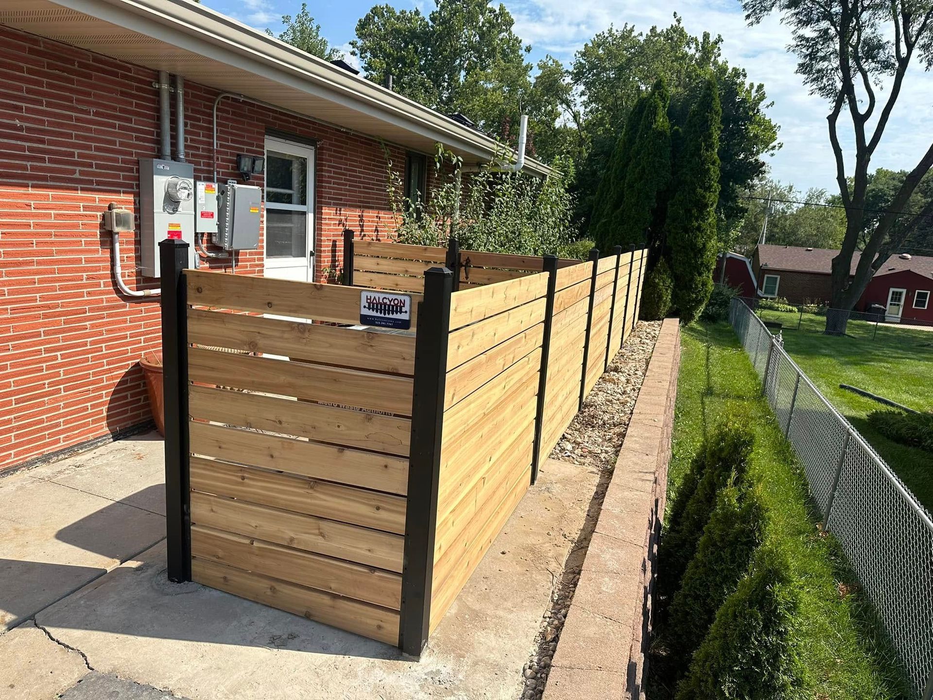 A wooden fence is sitting in front of a brick house.