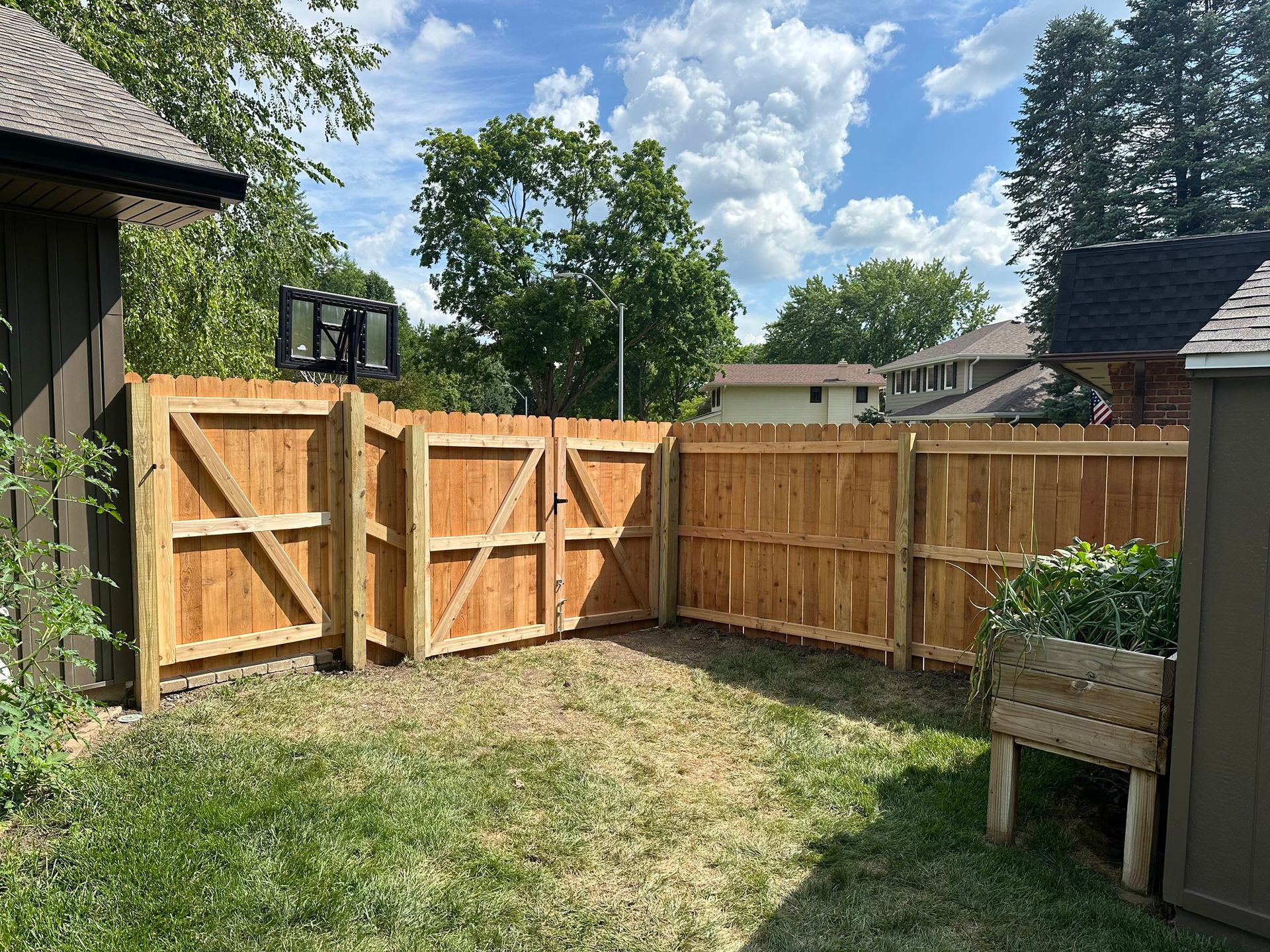 A wooden fence with a gate in the backyard of a house.