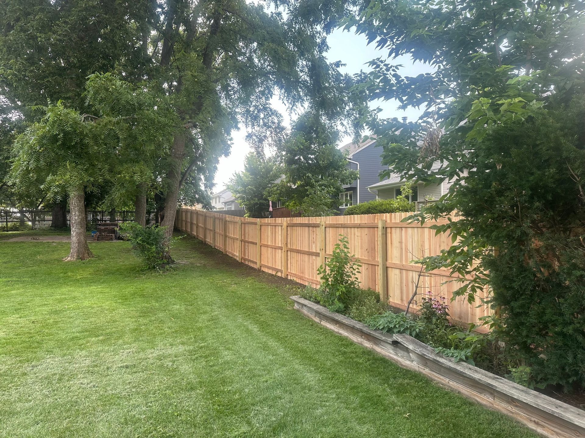 A wooden fence surrounds a lush green yard.