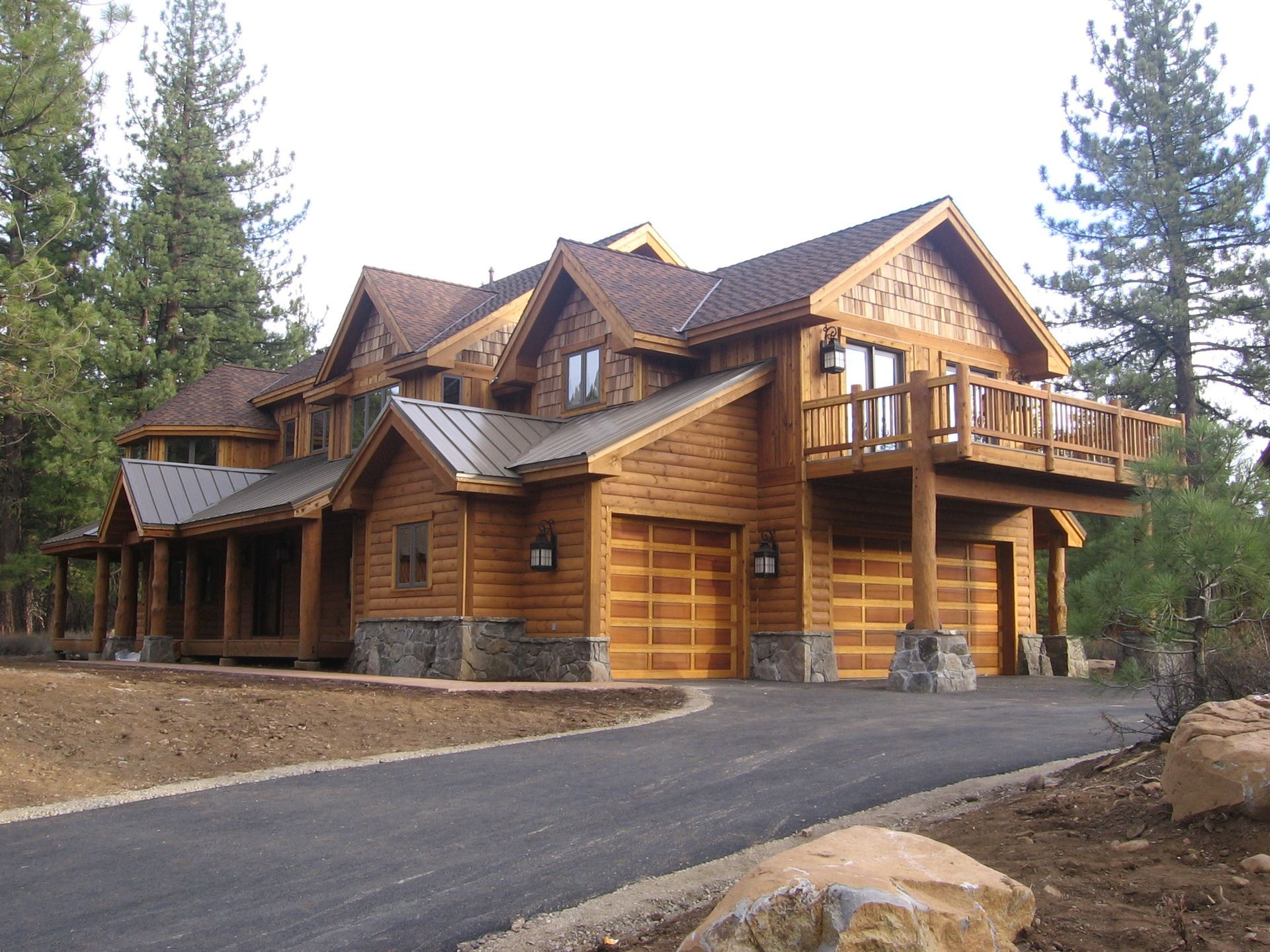 A large wooden house with a metal roof is surrounded by trees