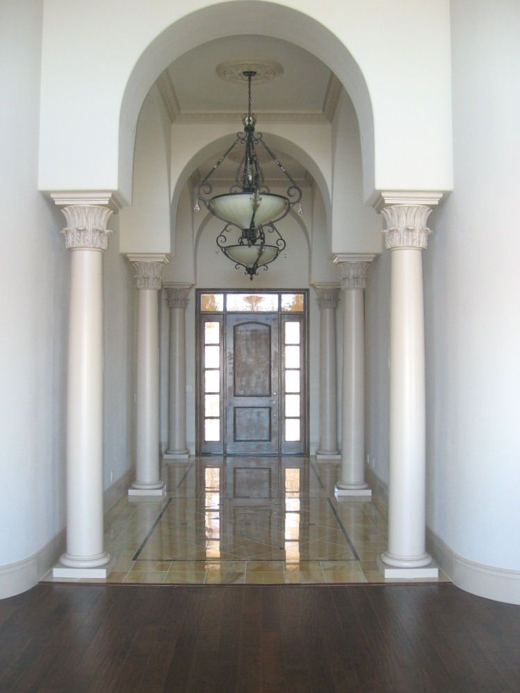 A hallway with columns and arches leading to a door