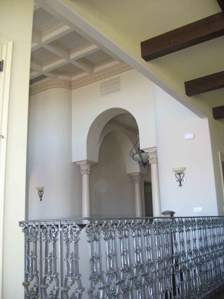 A balcony with a wrought iron railing and arched ceiling