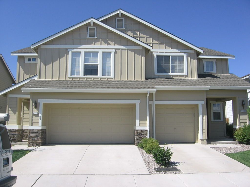 A house with two garage doors and a blue sky in the background