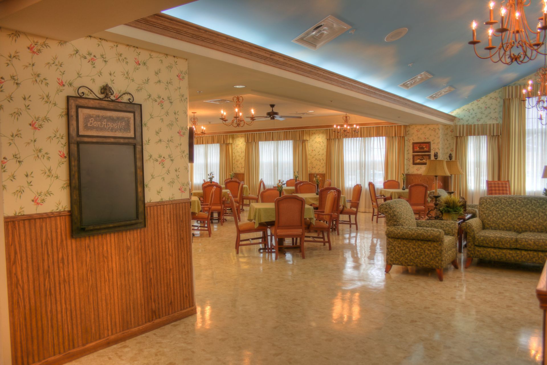 A large dining room with tables and chairs and a blue ceiling.