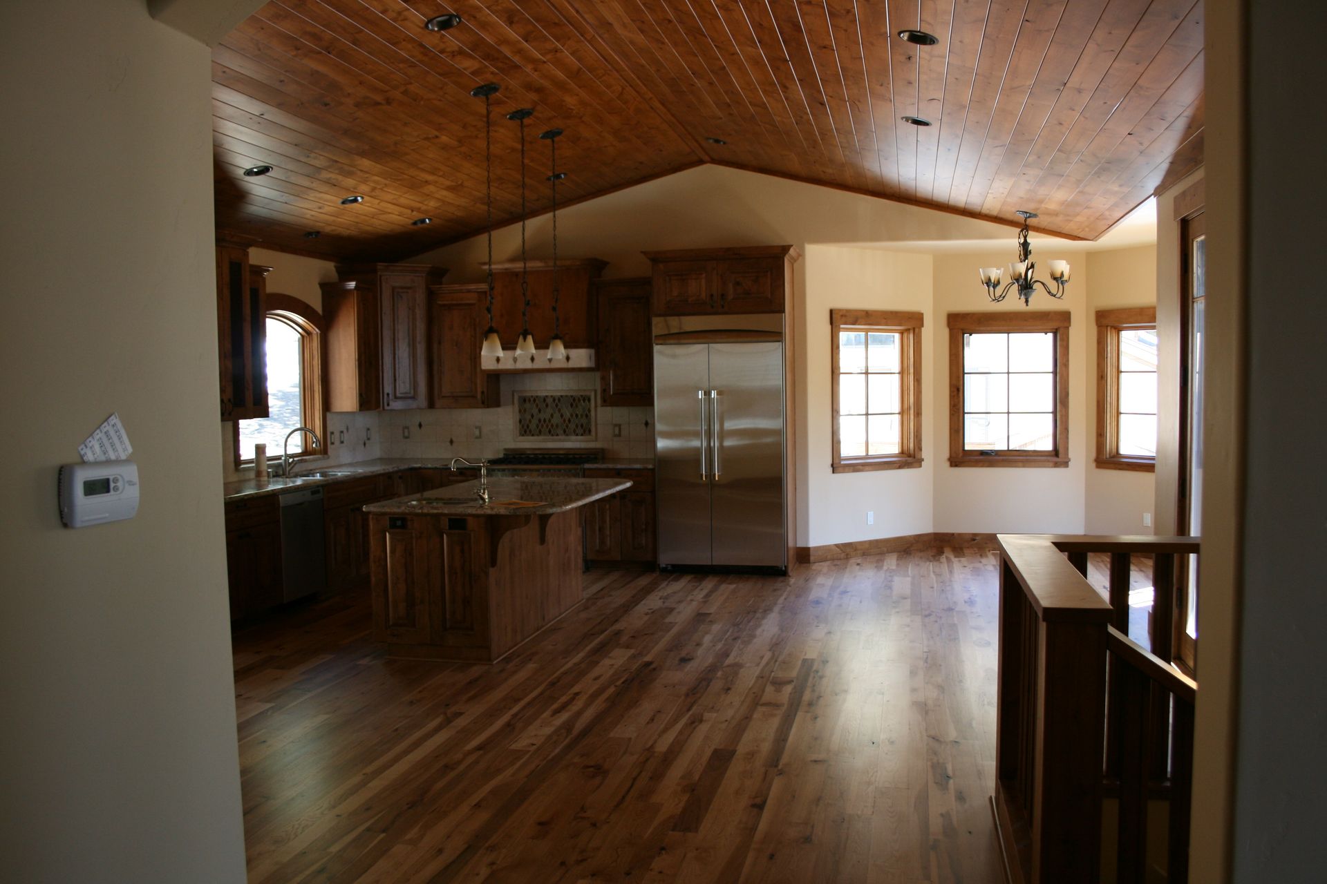 An empty kitchen with hardwood floors and stainless steel appliances