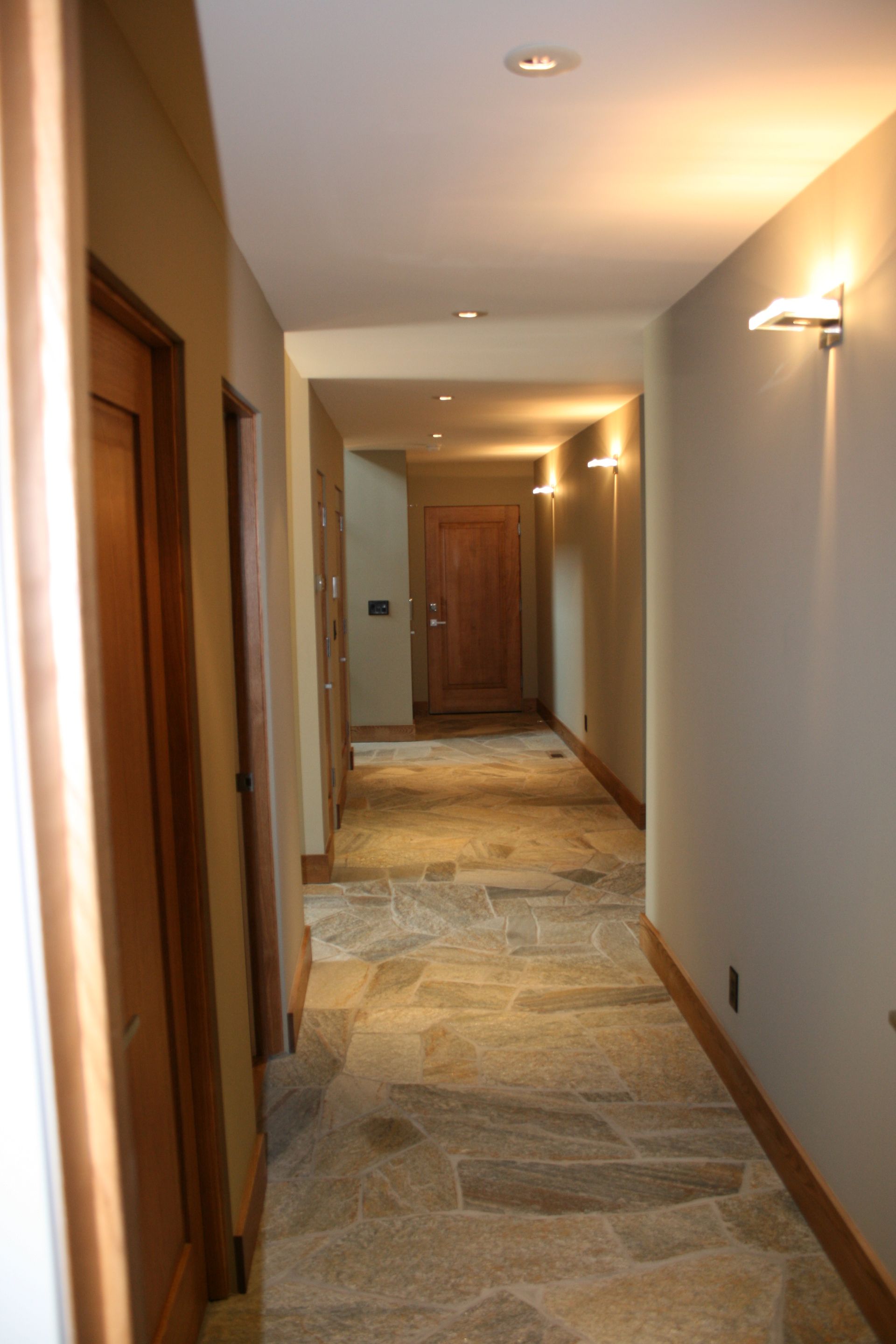 A hallway with a stone floor and a wooden door
