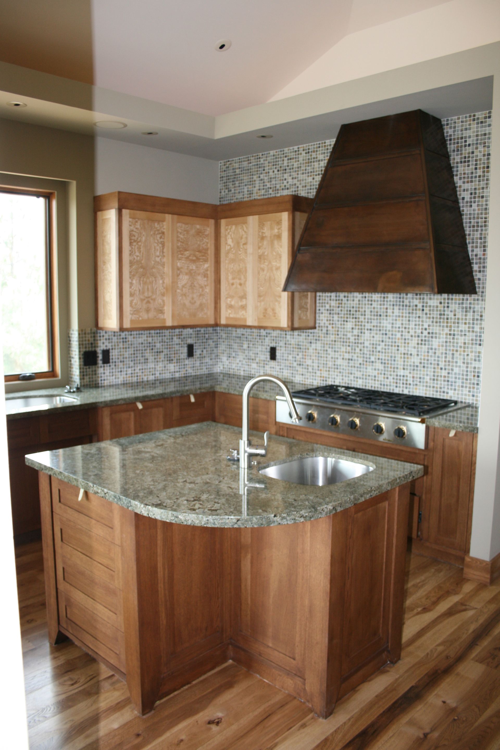 A kitchen with wooden cabinets , granite counter tops , stainless steel appliances and a large island.