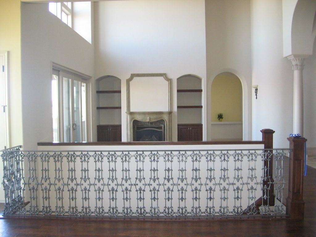 A staircase with a wrought iron railing and a fireplace in the background