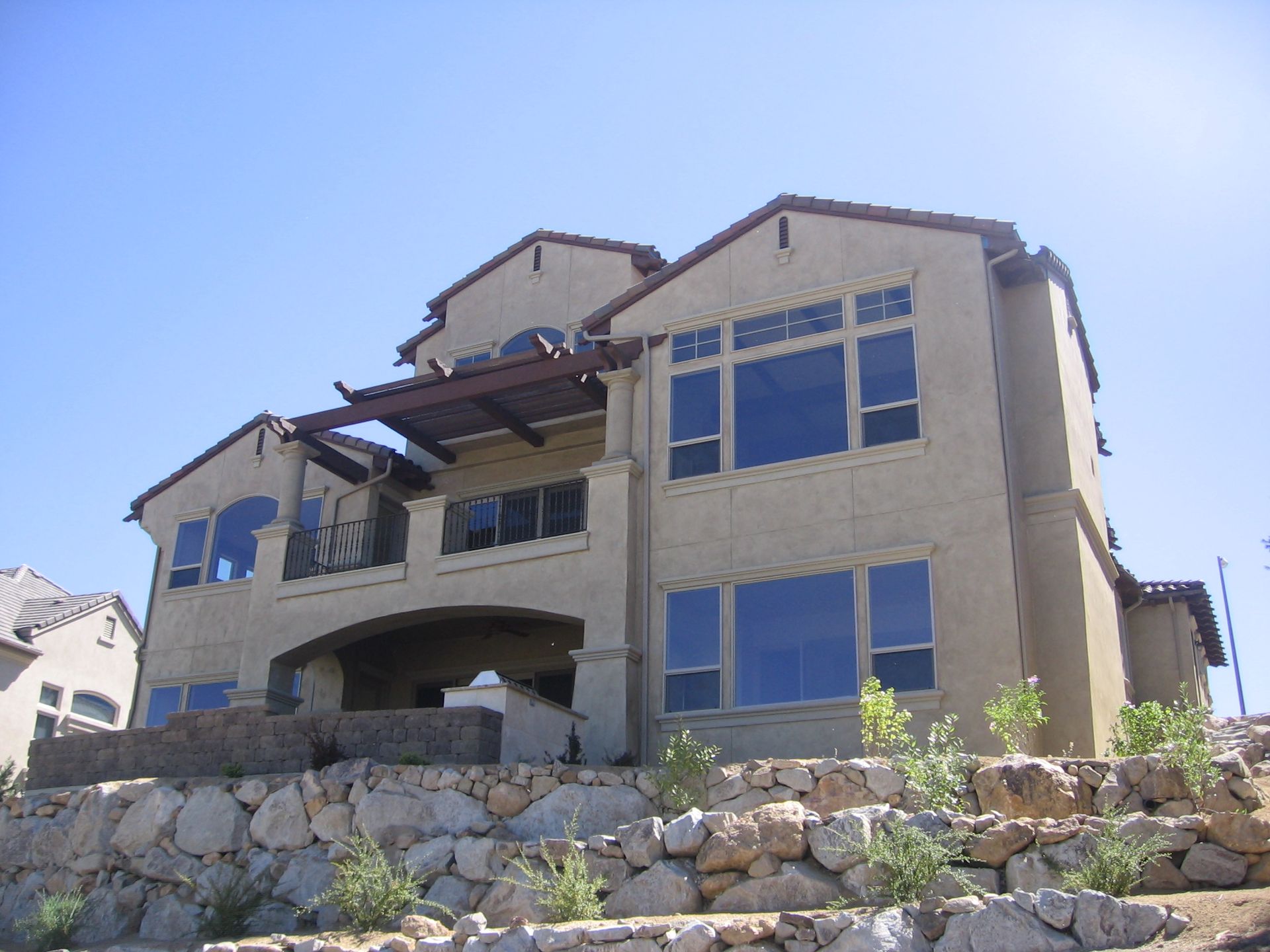 A large house sits on top of a rocky hillside
