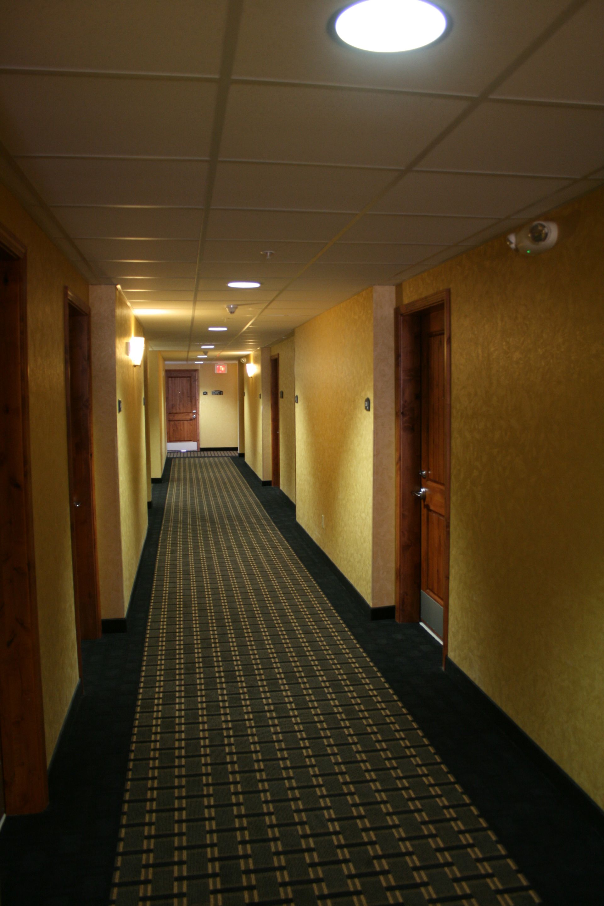 A long hallway in a hotel with a black carpet
