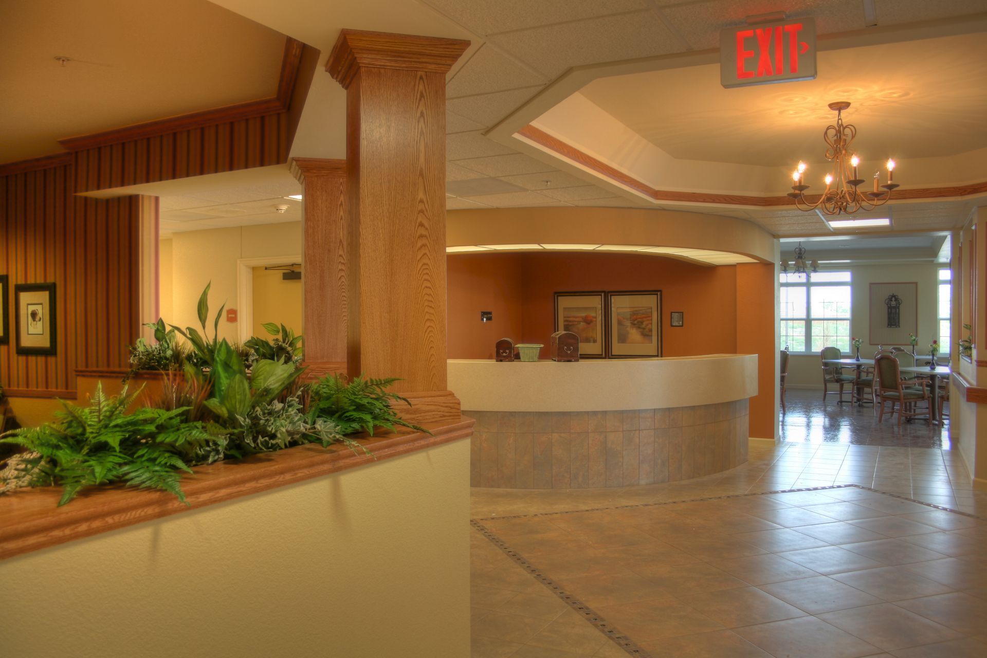 A lobby with a reception desk and a red exit sign.