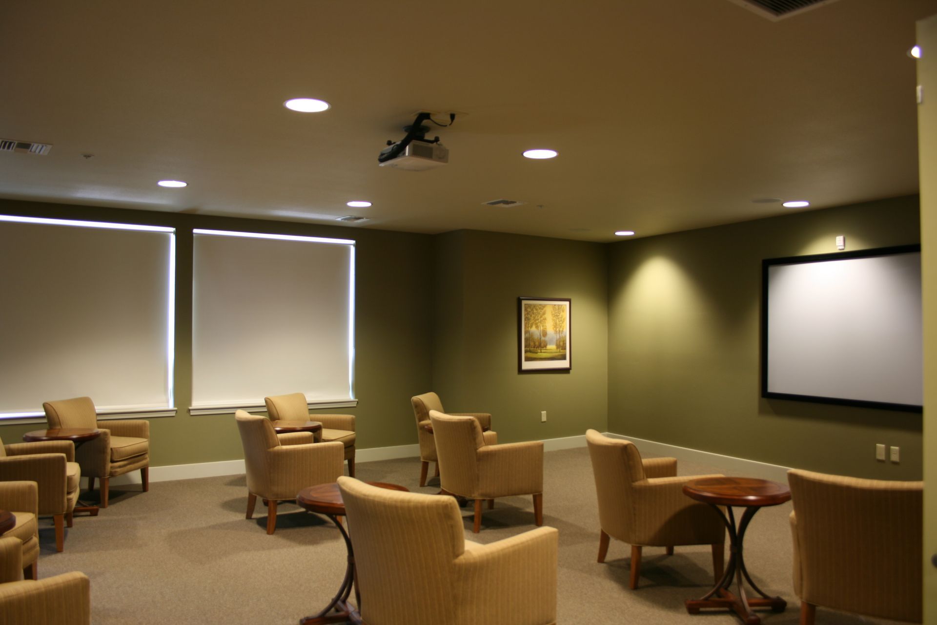 A room with chairs and tables and a large screen