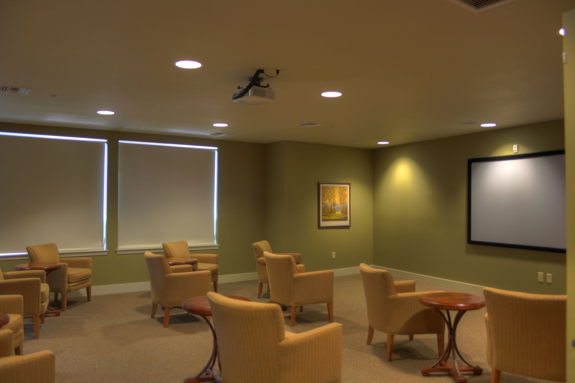 A room with chairs and tables and a large screen