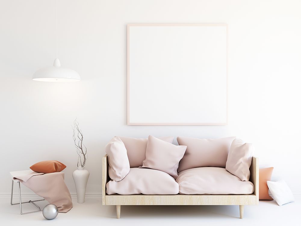 A living room with a couch and a picture frame on the wall.