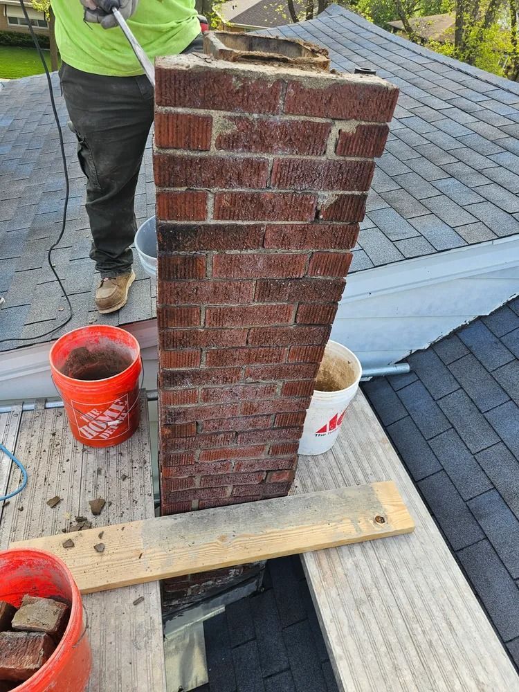 Person repairing a brick chimney on a rooftop.