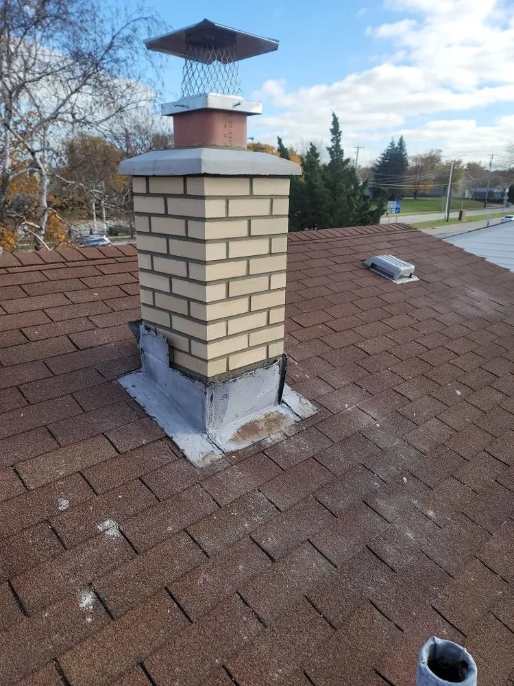 Gabled house facade with brick and siding, a large window, and blue sky.