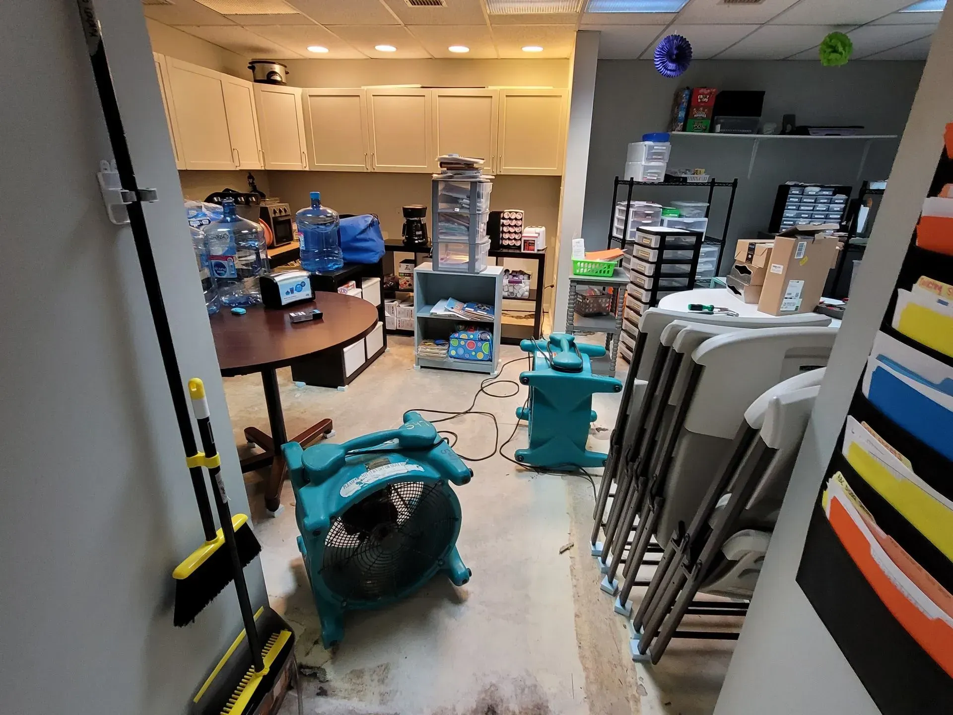 A room filled with chairs , a table , and a fan.