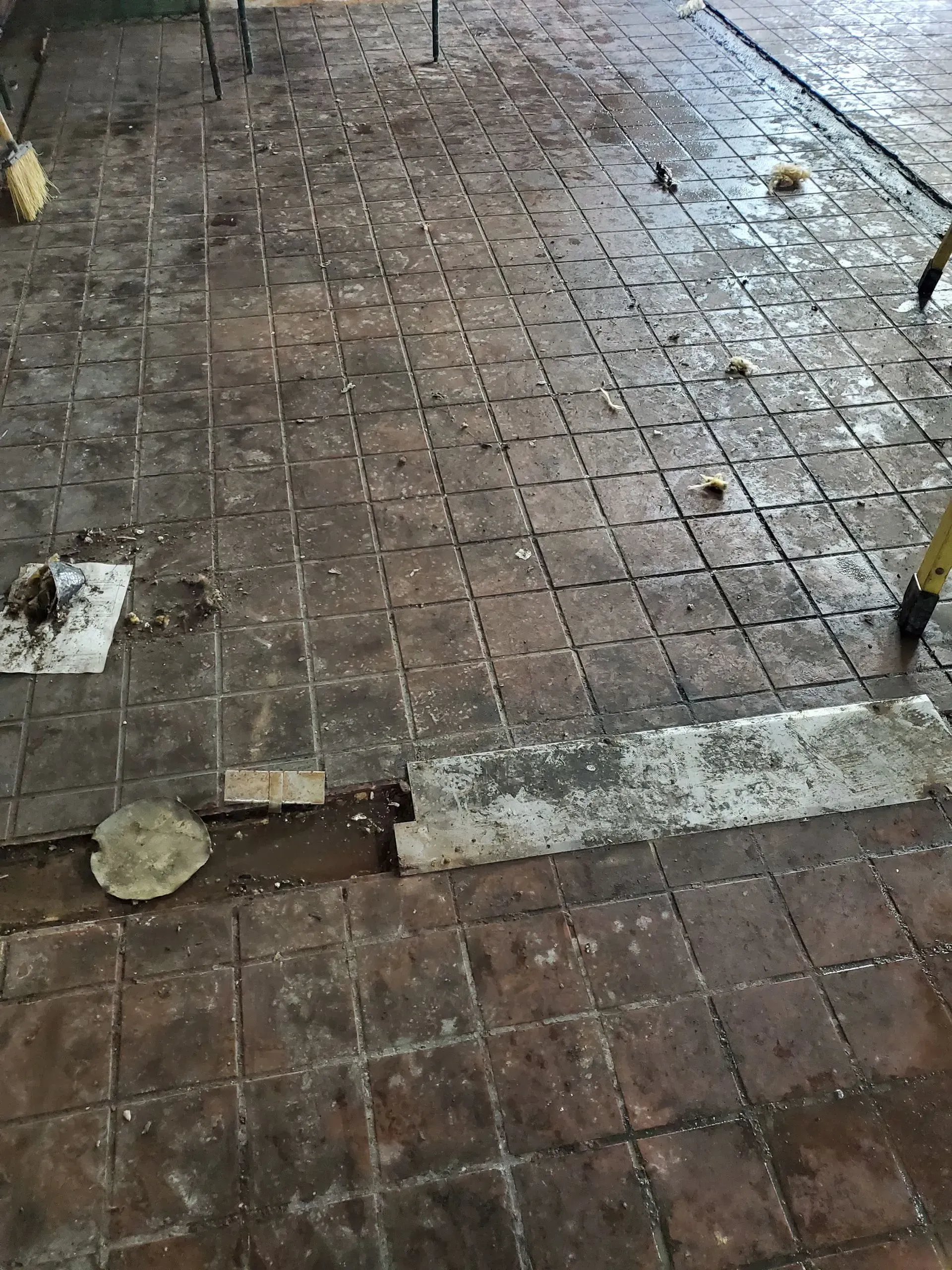 A person is cleaning a dirty tiled floor with a mop.