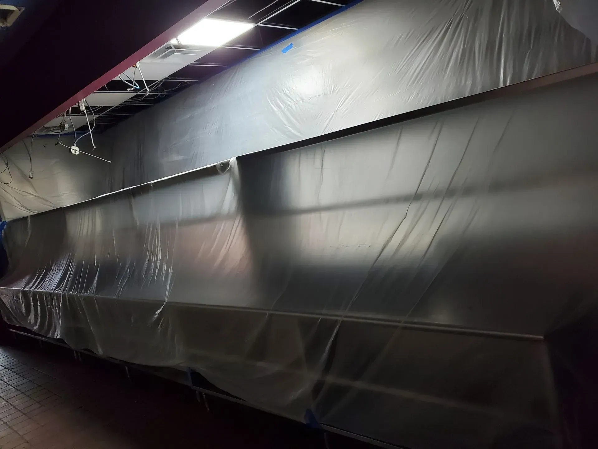 A large stainless steel wall is covered in plastic.