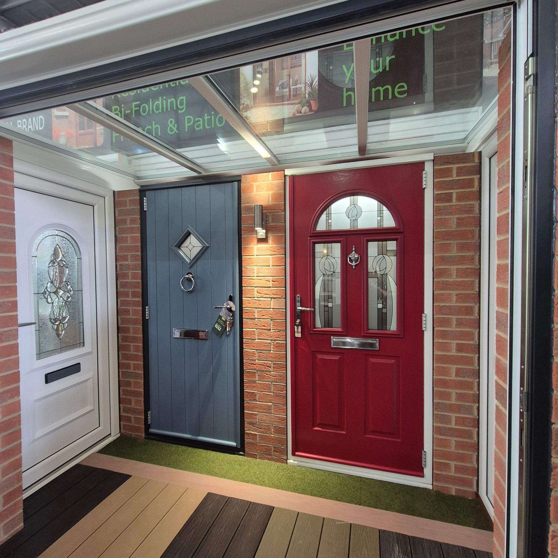 Three colorful front doors on display under a glass awning.