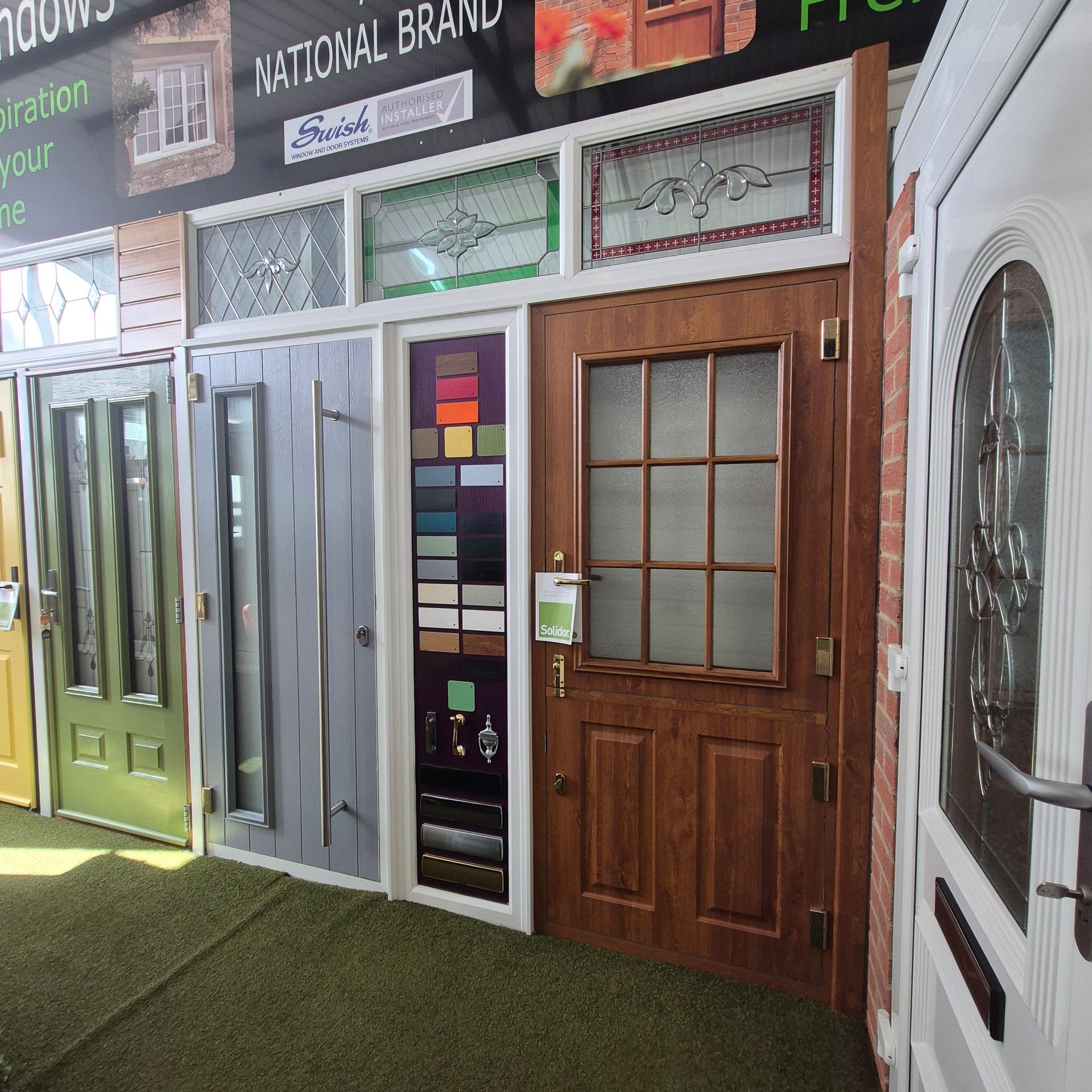 Various doors displayed at a store. Colors: green, gray, brown, white. The setting is likely a showroom.