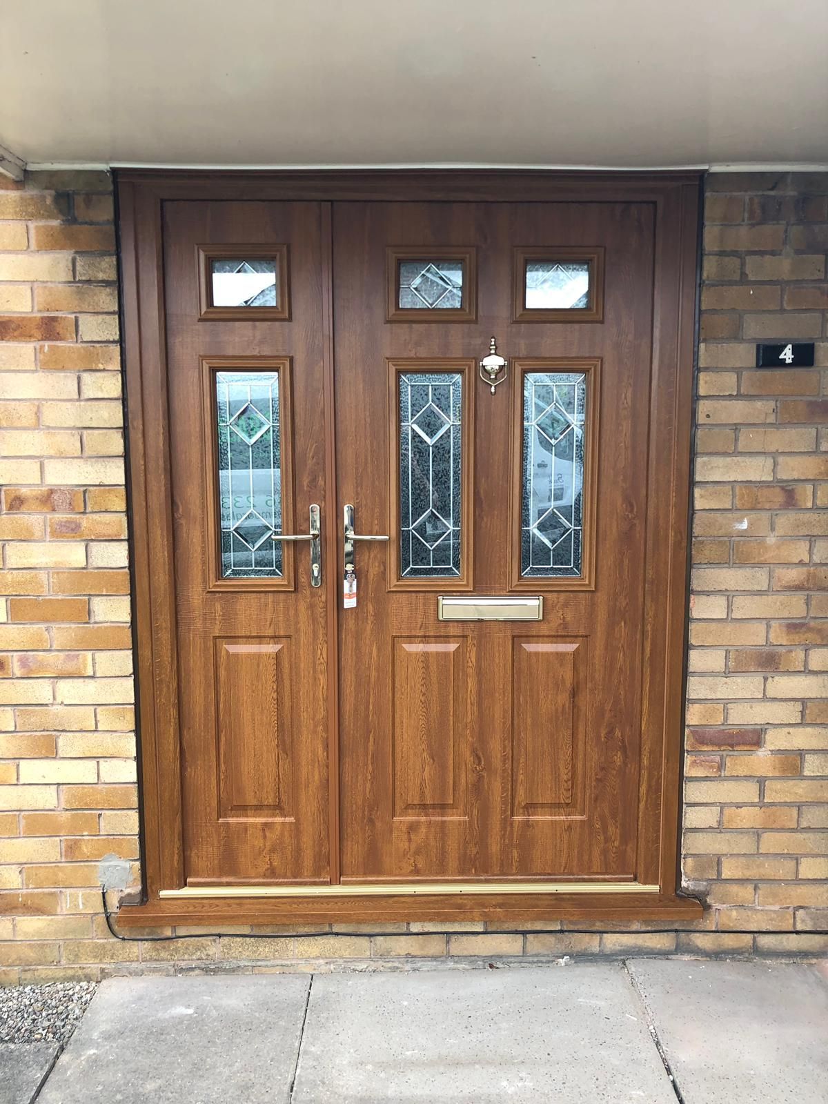 Brown double front doors with glass panels and a brick exterior.