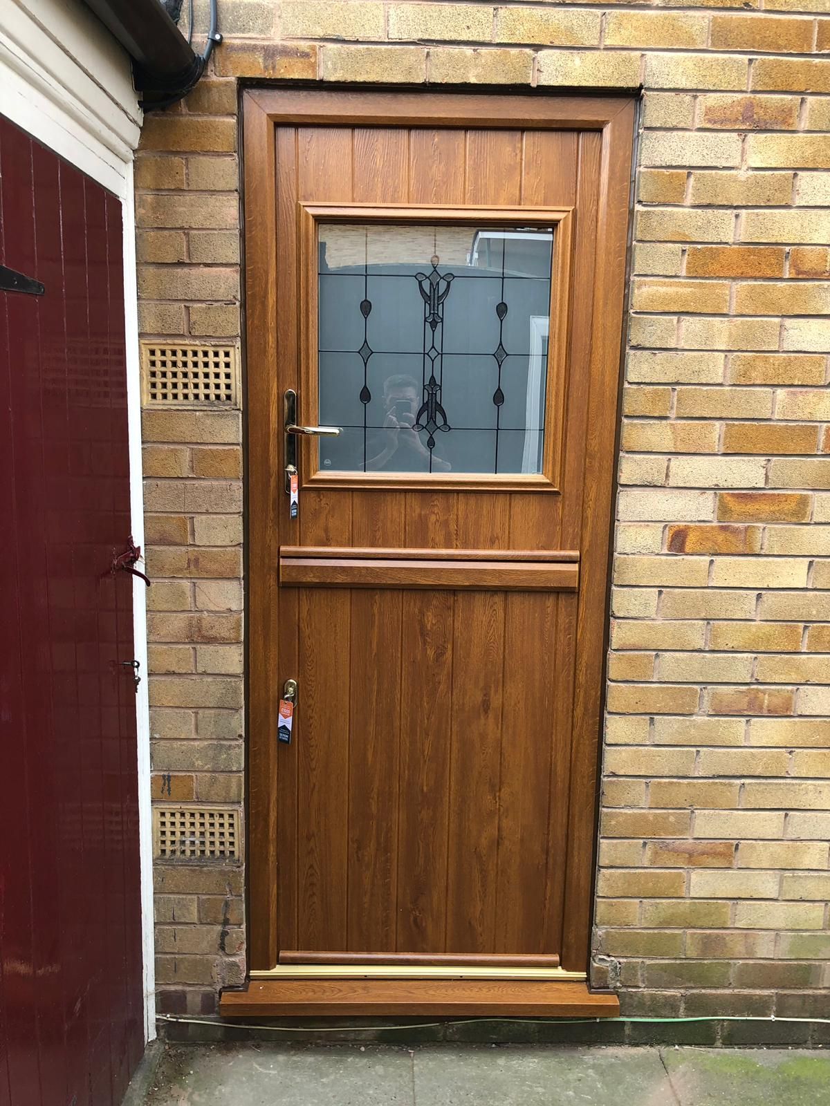 Brown wooden door with glass pane, set in a brick wall.
